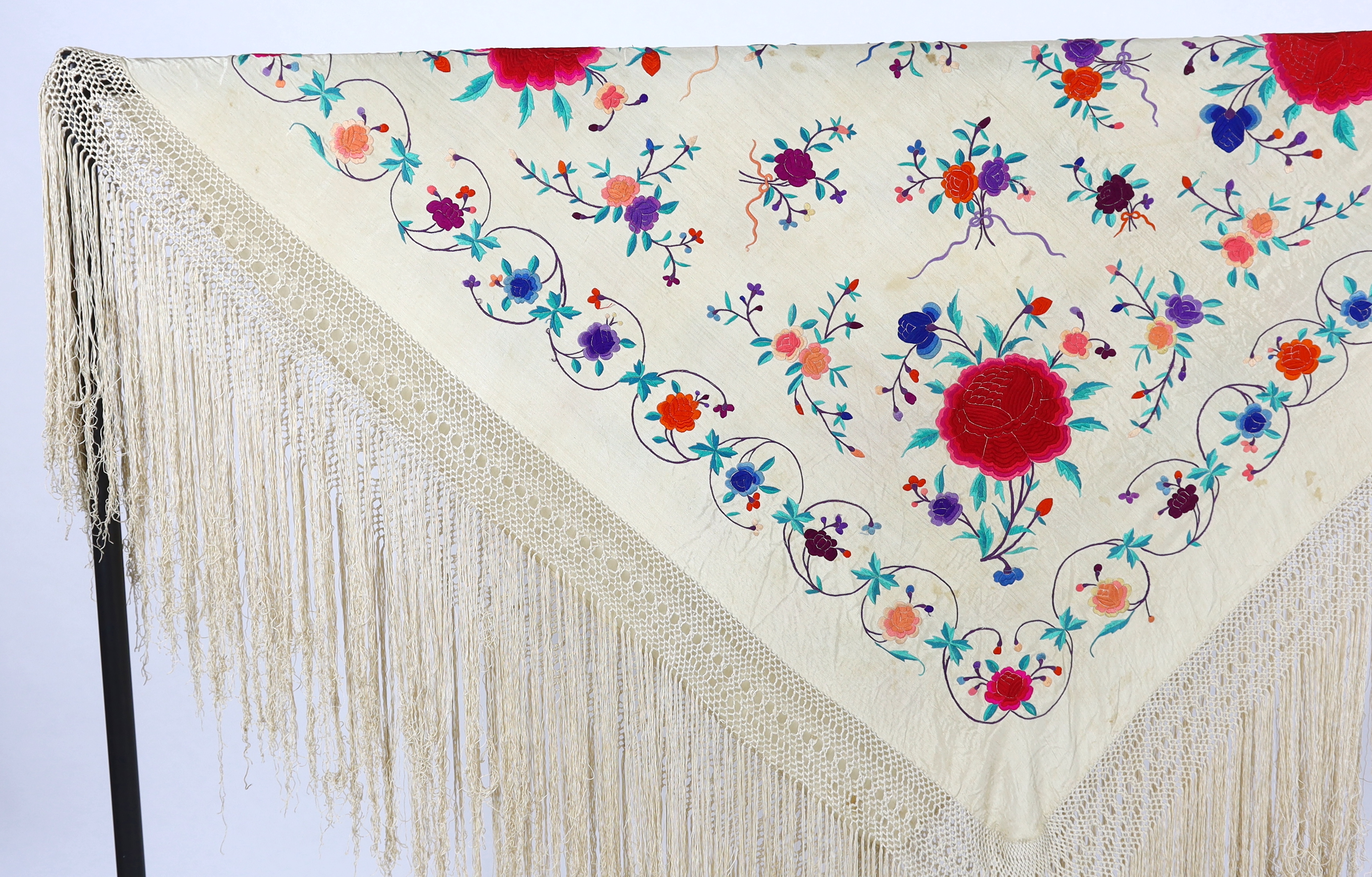 A late 19th / early 20th century cream silk fringed shawl, embroidered with all over polychrome silk floral motifs, 130 x 150cm not including fringe